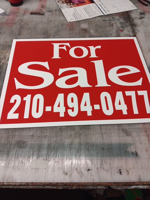 Red and white For Sale real estate sign with phone number