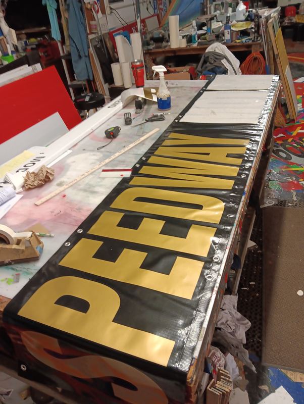 Gold lettered metal sign panel laid out on the workbench