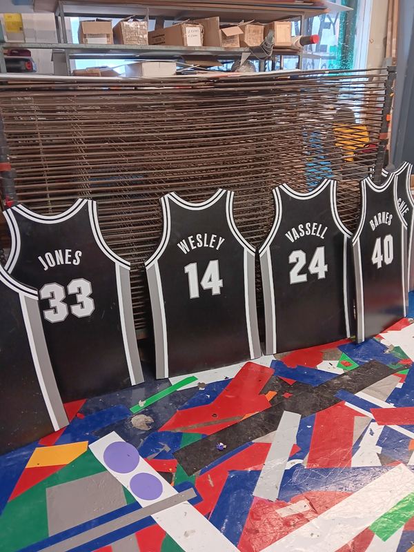 Row of screen printed custom basketball team jerseys with names and numbers