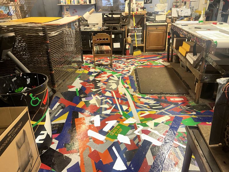 Screen printing shop floor covered in ink-stained proof sheets